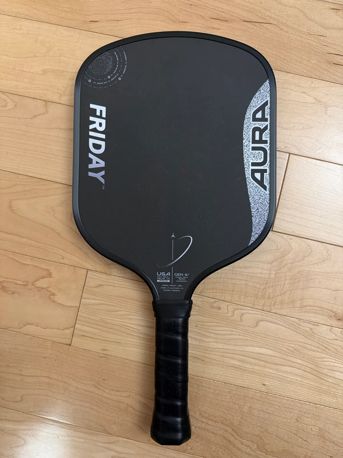 Friday Aura Widebody paddle lying on a wood floor